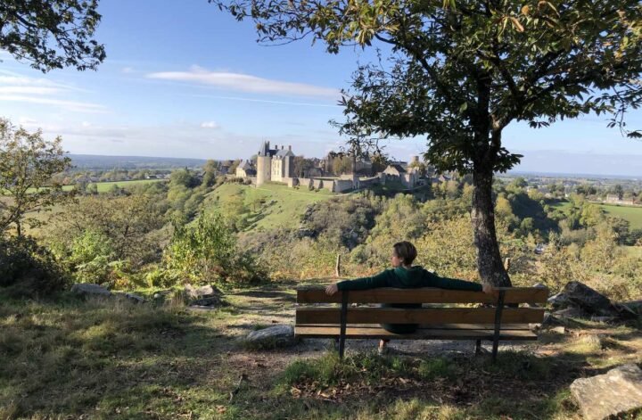 zdjecie ławki i osoby siedzacej na niej , podziwiajacej widok zamku w sainte suzanne
