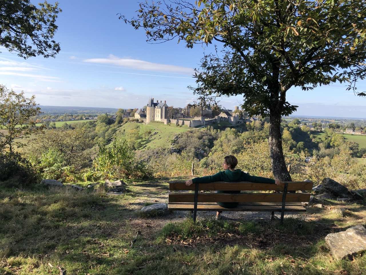 zdjecie ławki i osoby siedzacej na niej , podziwiajacej widok zamku w sainte suzanne