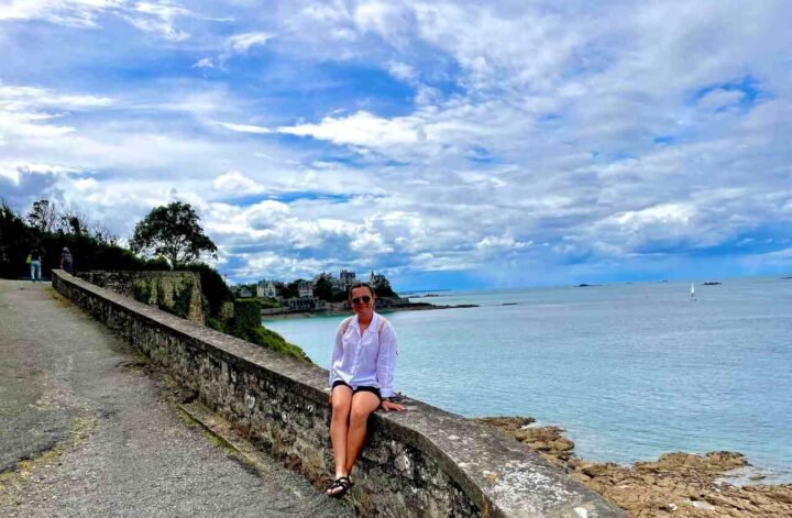Kobieta siedząca na murku, obserwuje morze i poszukuje szczęścia